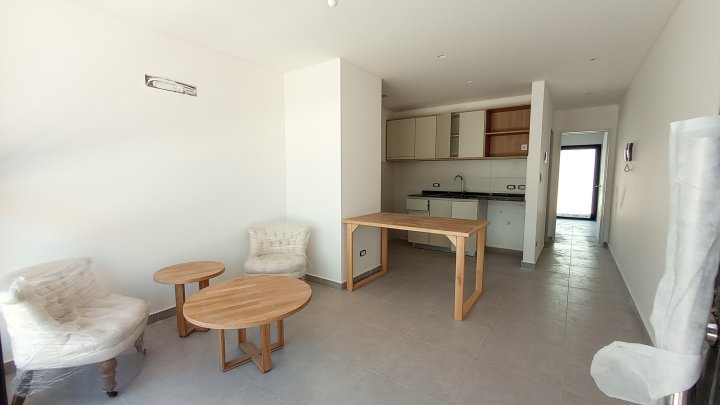 Estar-comedor con cocina integrada en un departamento de dos ambientes de Cattaleya