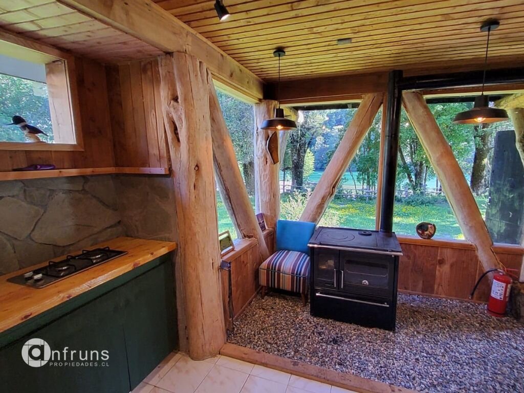 Spacious interior with wood floors, exposed beams, and large windows offering views of the surrounding nature.