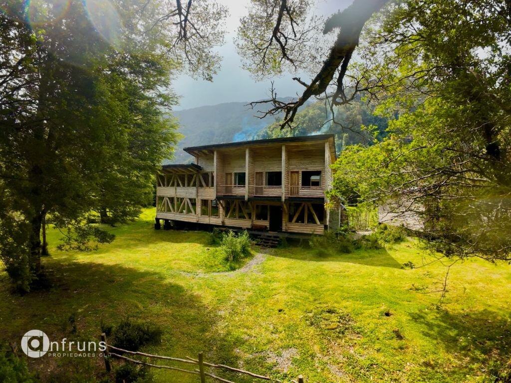 Exterior view of the lodge with a wooden deck and stone accents, surrounded by trees and lawn.